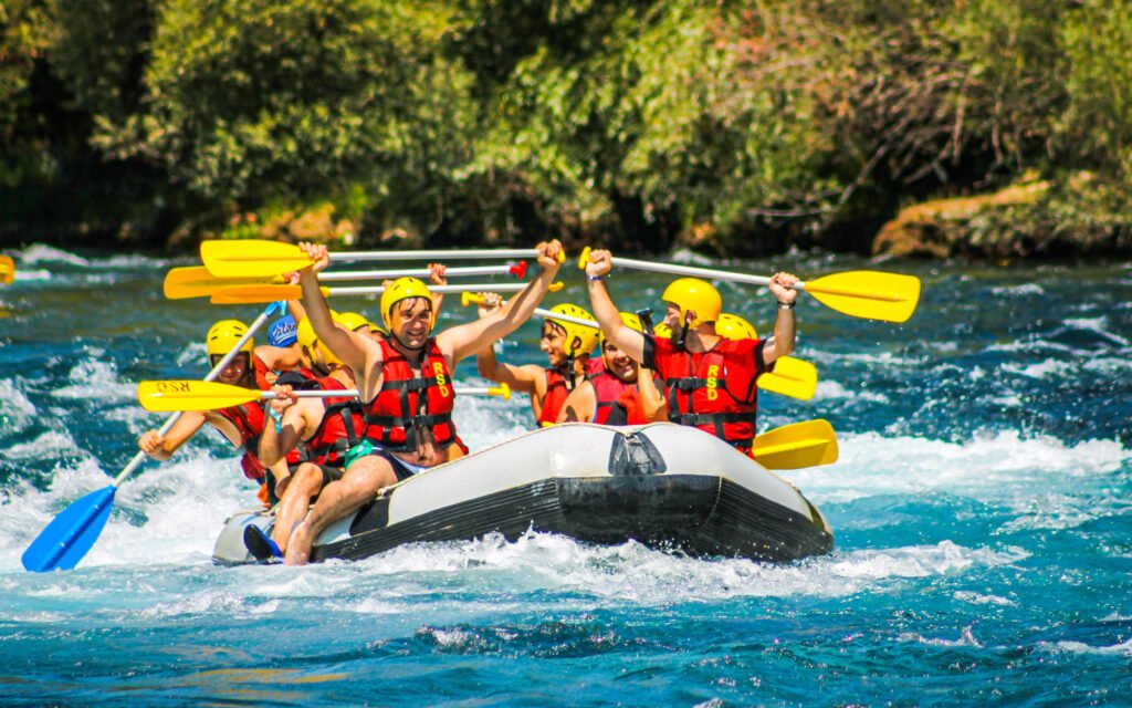 Dalaman Rafting Fiyatları 2025 ile rafting yapan bir grup kürekleri havaya kaldırıyor ve eğleniyor